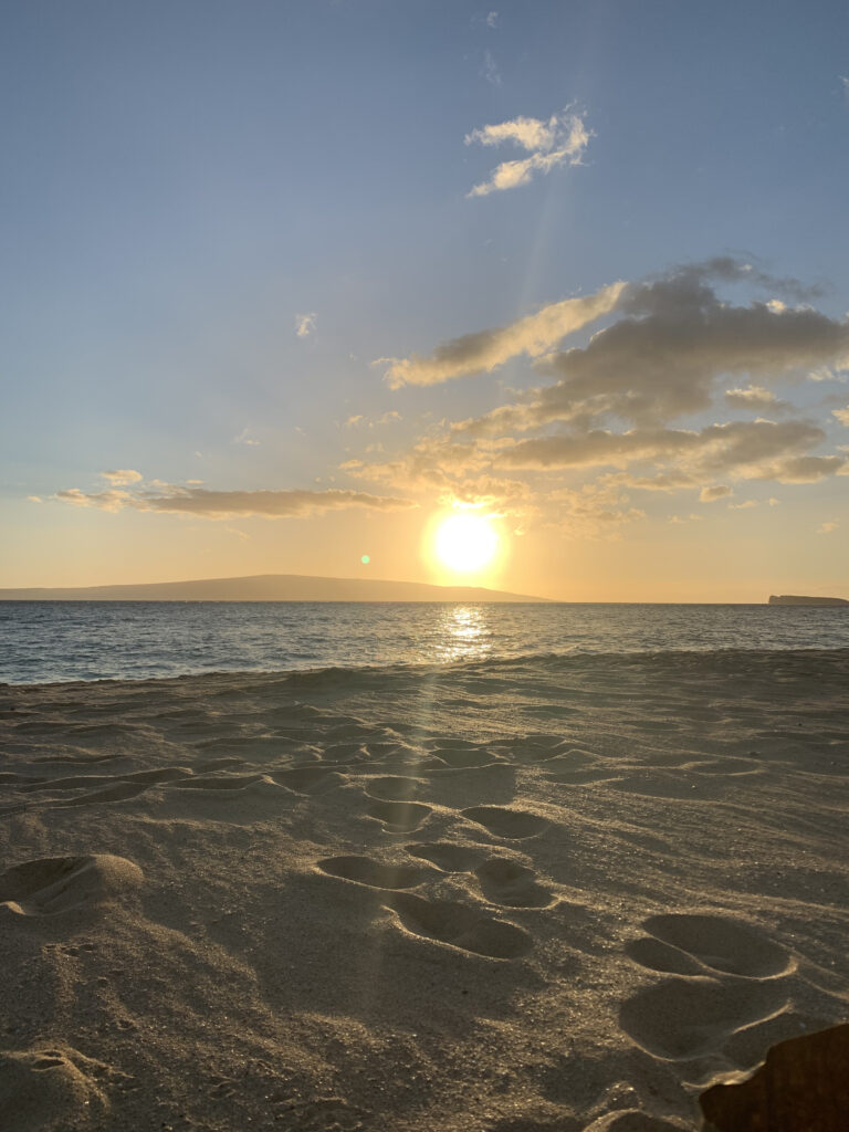 sunset on a beach with sand and the ocean