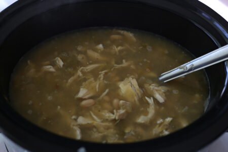 Chicken soup in a crockpot with a silver spoon