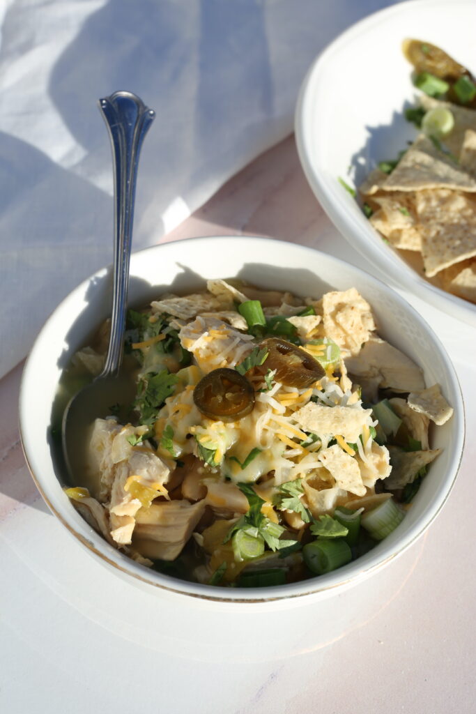 white chicken chili in a bowl with a silver spoon