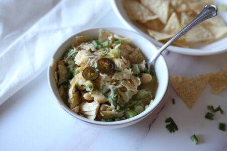 Chicken chili with jalapeños on top in a white bowl