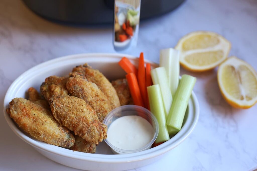 crispy wings in a bowl with carrots and celery