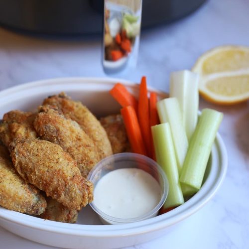 crispy wings in a bowl with carrots and celery