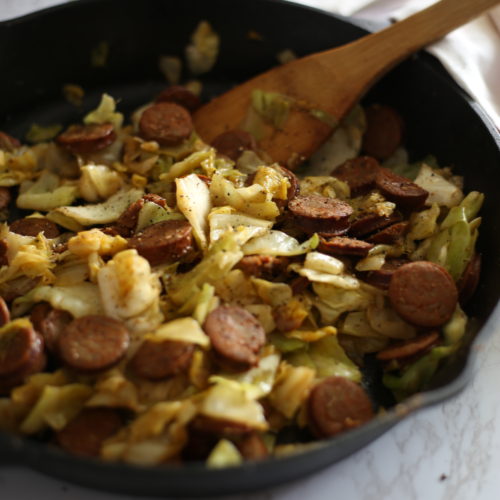 sliced chicken sausage and cabbage in a black cast iron skillet