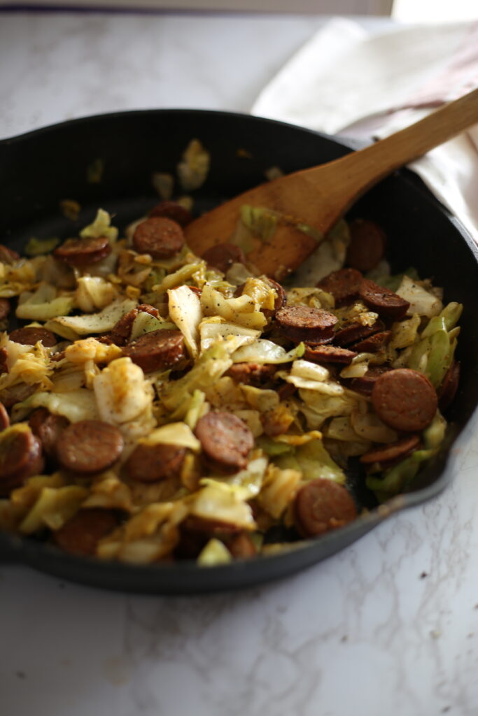 sliced chicken sausage and cabbage in a black cast iron skillet