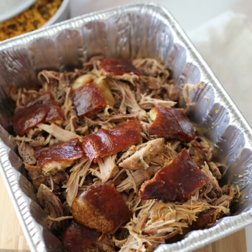 Shredded Puerto Rican pork shoulder in a foil pan.