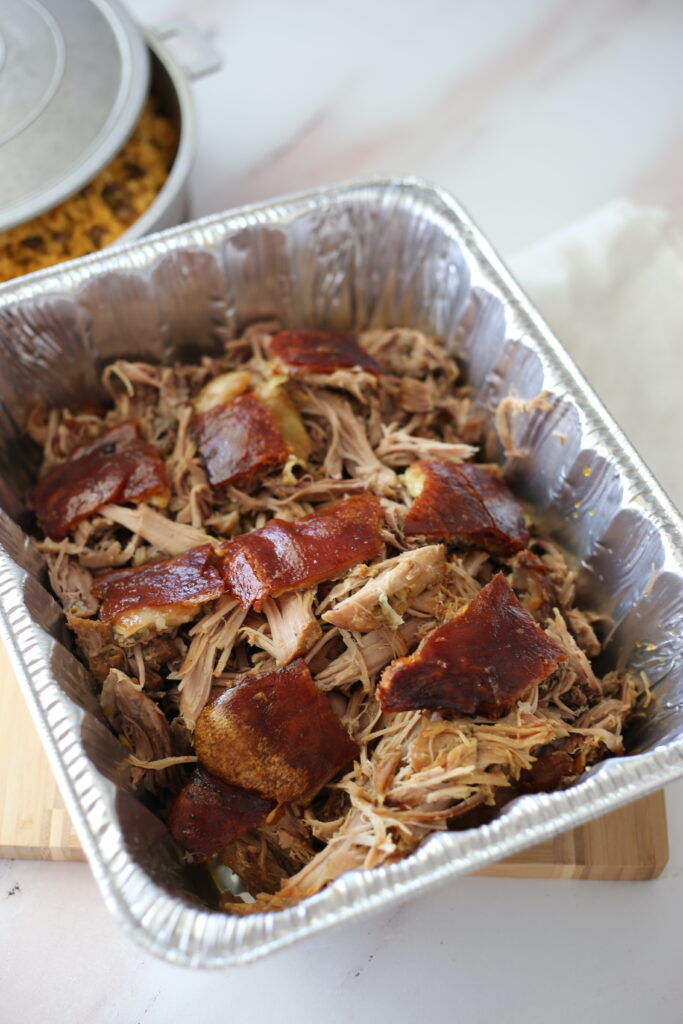 Shredded Puerto Rican pork shoulder in a foil pan.