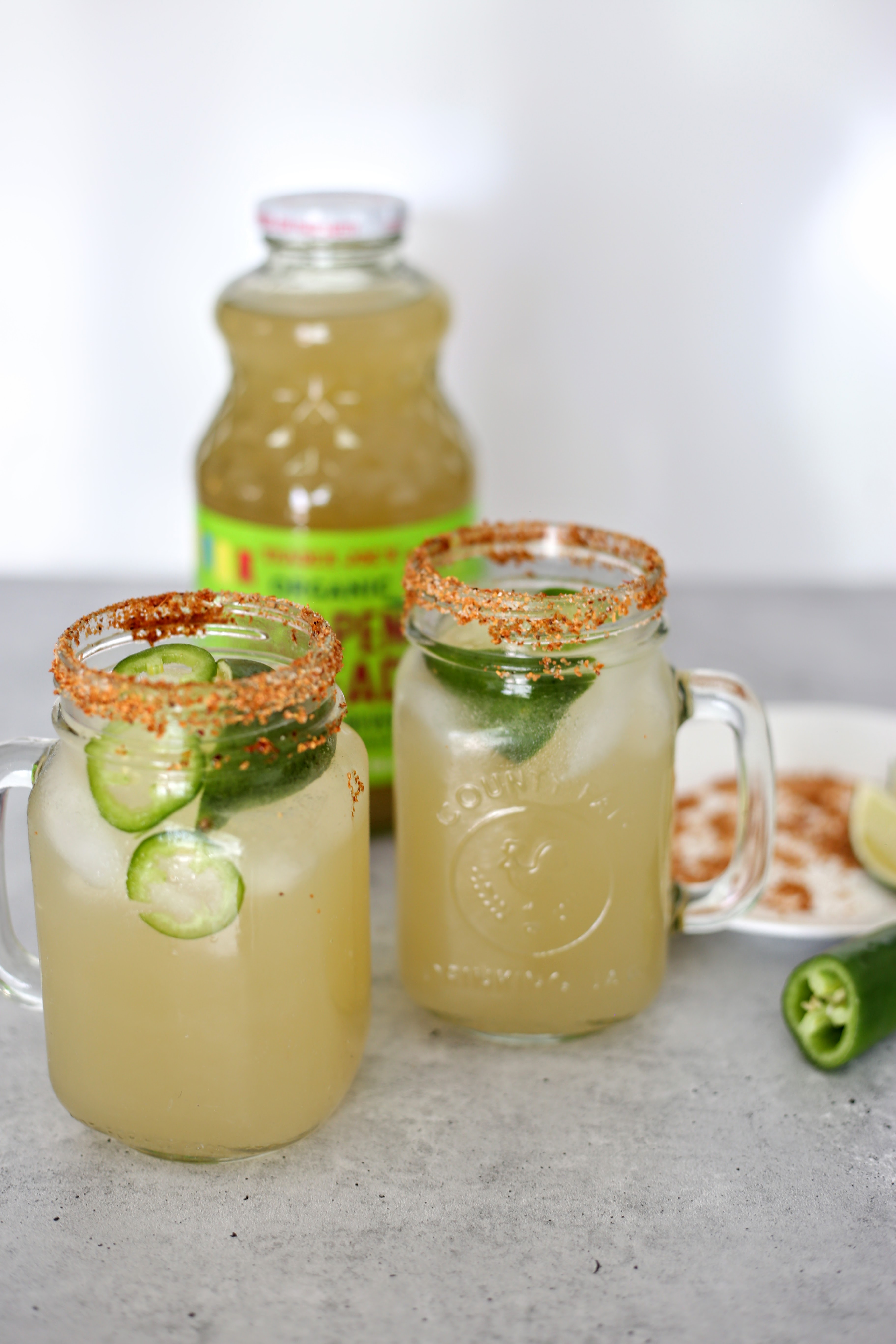 Two clear mason jars filled with margarita's with a red salted rim.