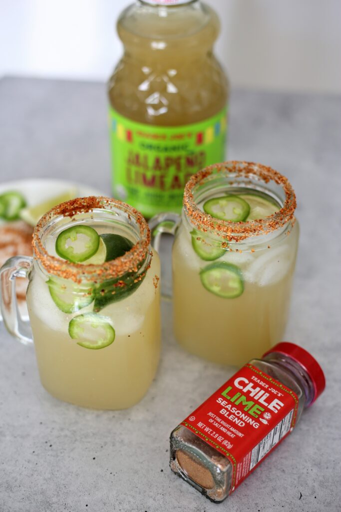 two mason jars filed with margarita drink with red salt around the rim.