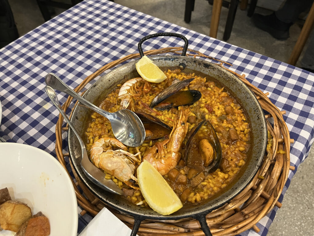 Paella in a paella silver pan on a checkered table cloth