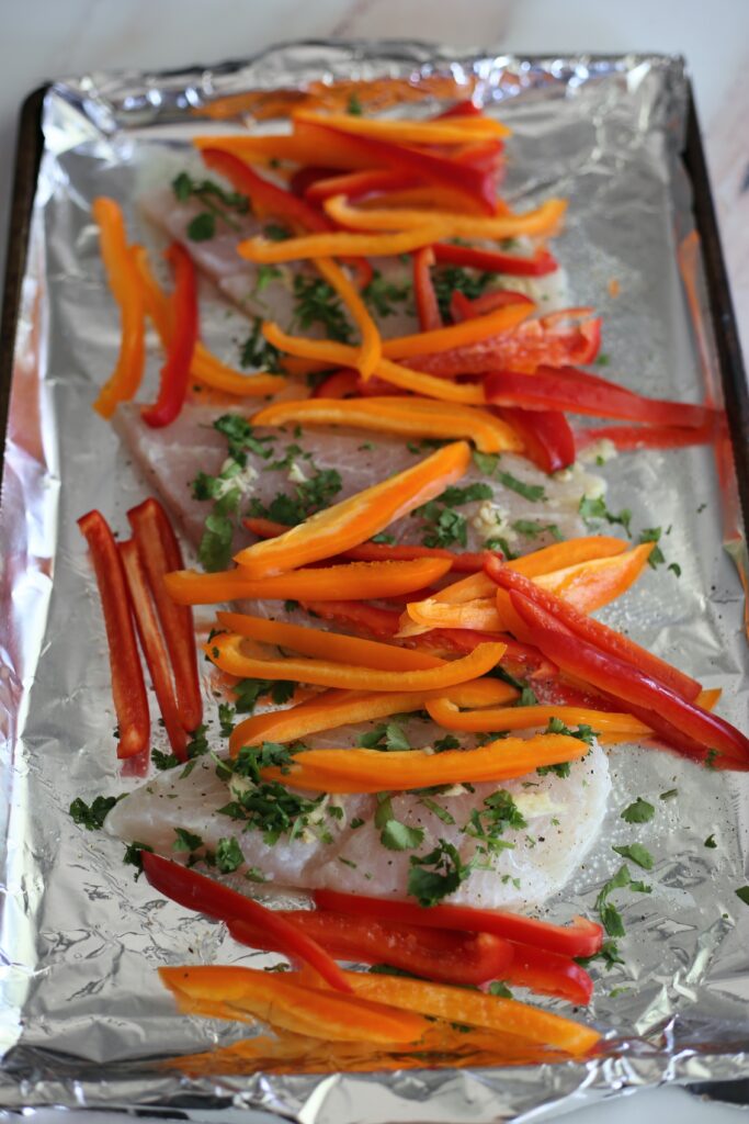 Bell Peppers and White Fish on a foil lined baking dish. 