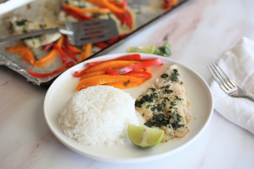 fish with rice and colorful bell peppers on a white plate