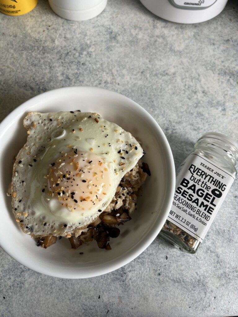 everything but the bagel seasoning oatmeal with an over easy egg on top in a white bowl.